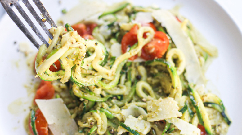 zucchini noodles served with pesto, parmesan, and tomatoes