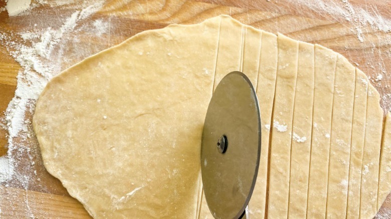 pizza cutter slicing dough