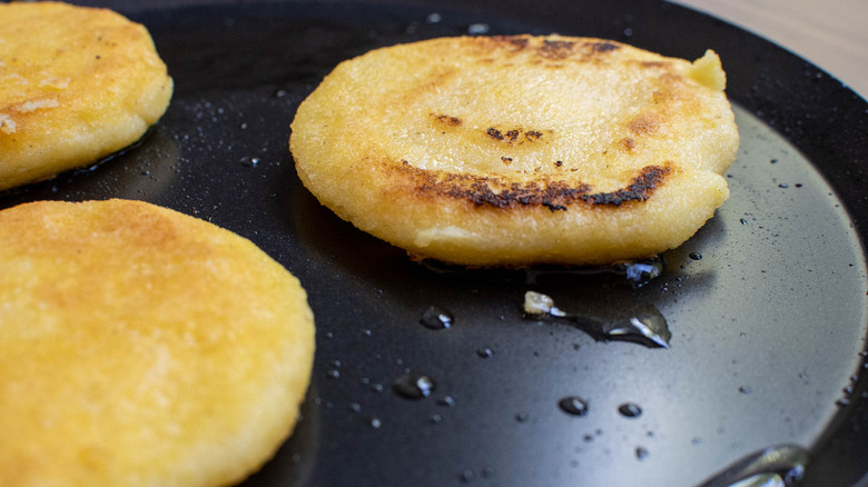 arepas frying in pan