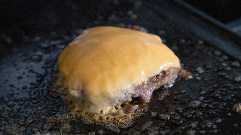 smash burger on griddle with cheese 