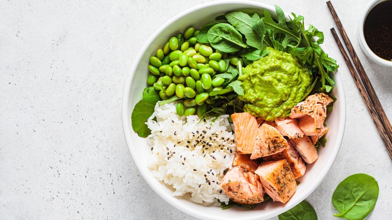 Salmon, rice, edamame, guacamole, and greens in bowl