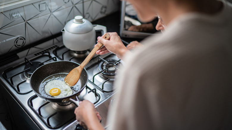 man frying egg on pan