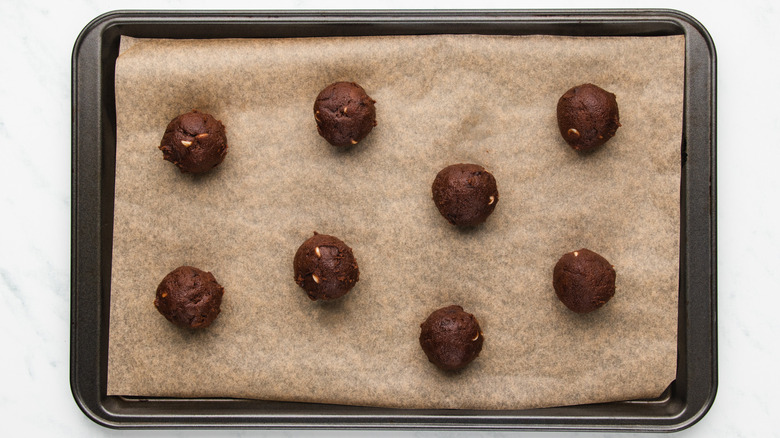 Cookie dough balls on lined baking sheet