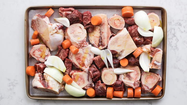 raw meat and vegetables on baking sheet