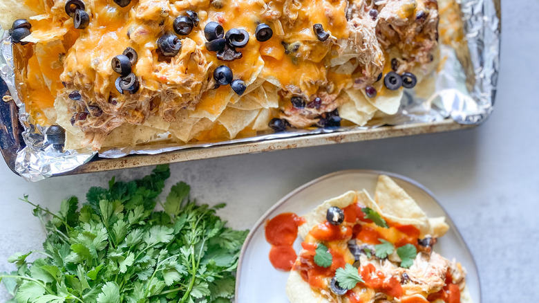 Nachos on plate beside tray of chips