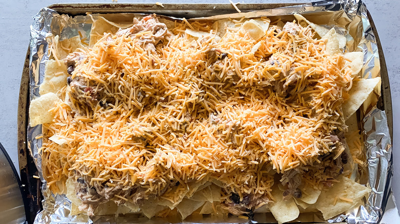 chips on baking sheet topped with chicken and cheese