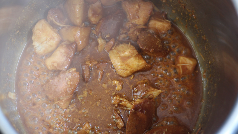 Cooking chicken and sauce in a pot on the stove