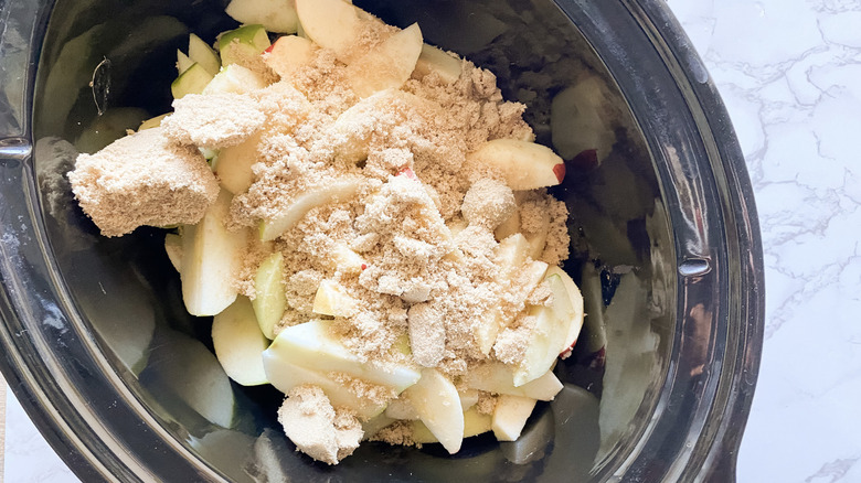 Ingredients for stewed apples in a slow cooker topped with brown sugar