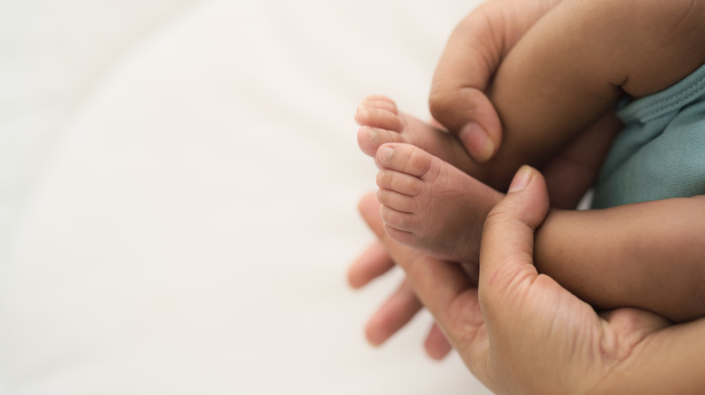 Baby feet held by adult hands