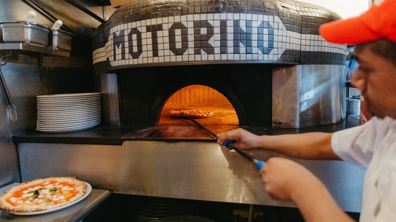 motorino worker firing pizza