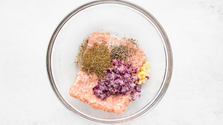 Ground chicken, onion, and herbs in mixing bowl