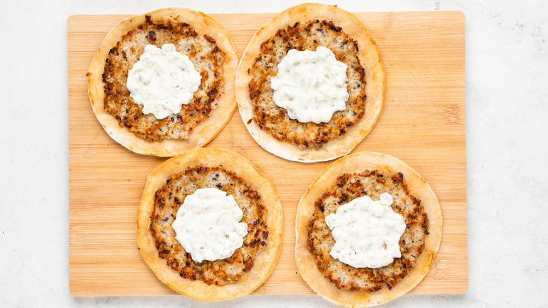 Smashed chicken gyro tacos on wooden cutting board