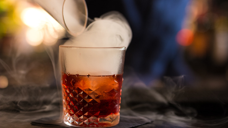 Bottle pouring smoke into a negroni