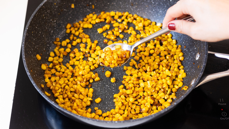 spoon removing corn from pan