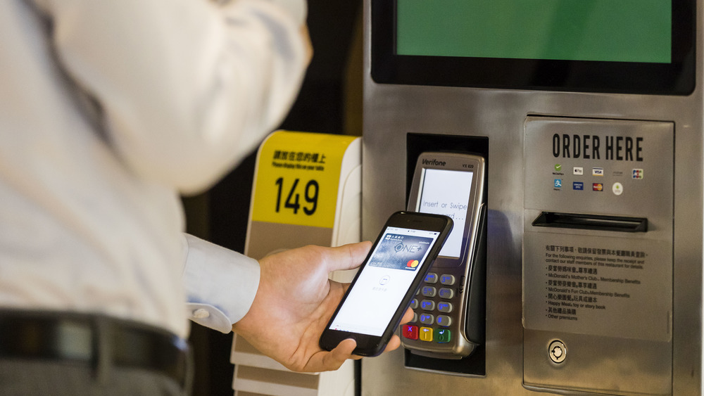 Customer with phone at McDonald's kiosk