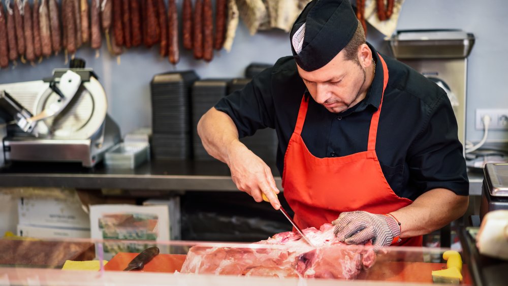 Butcher removing bone from a cut of ham