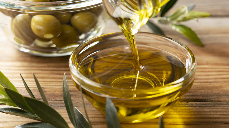 Olive oil pouring into a glass bowl