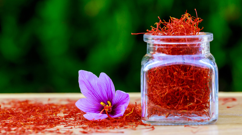 Saffron in a jar next to a saffron flower