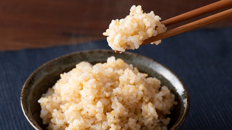 Chopsticks picking up brown rice