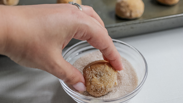 dipping a dough ball in sugar