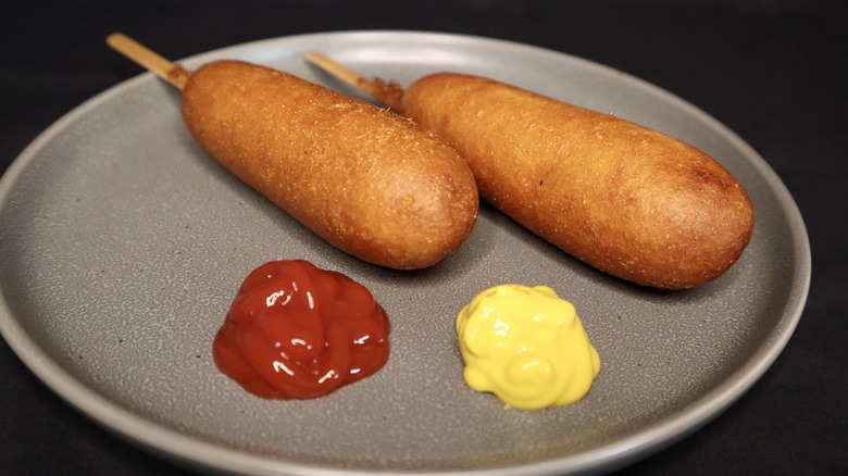 Corn dogs on plate with ketchup and mustard