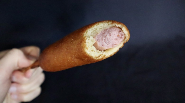 Hand holding corn dog with bite taken out