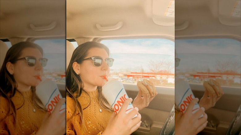 Woman eating Sonic burger in car