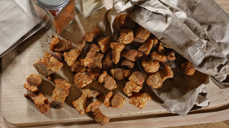 Pork cracklins pouring out of paper bag onto cutting board