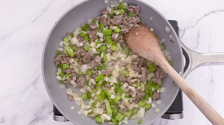 sausage in a skillet with onion and celery 