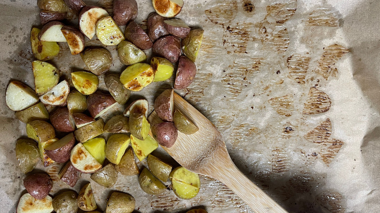 Roasted potatoes and wooden spatula on sheet pan