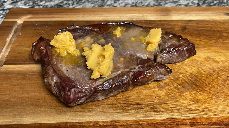 Steak with butter on cutting board