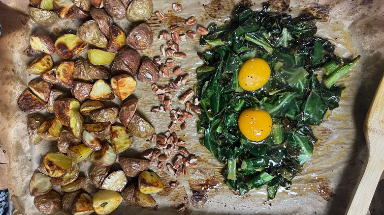 Potatoes, pecans, and collard greens with eggs on sheet pan