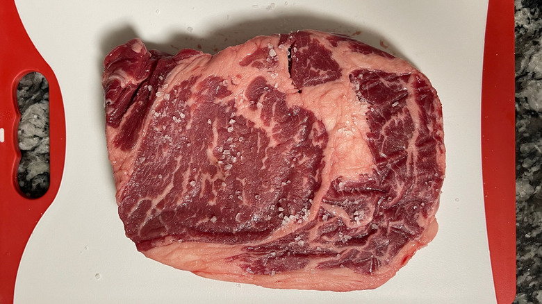 Raw salted steak on cutting board