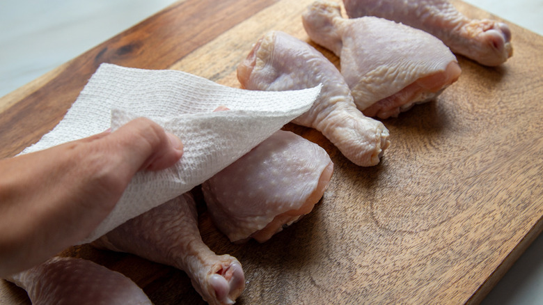 patting chicken drumsticks with towel