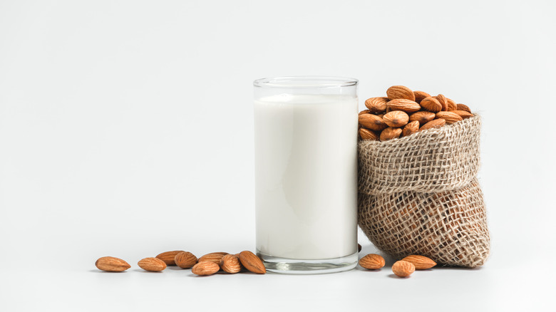 Glass of almond milk next to bag of almonds