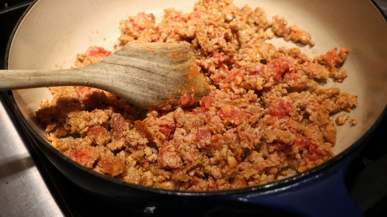 crumbled sausage in pan with wooden spoon