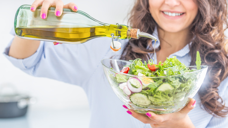 A woman putting oil on salad