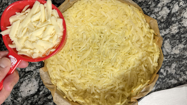 adding shredded cheese to hash brown crust