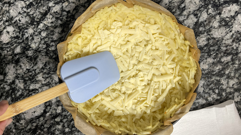 spreading cheese on hash brown crust