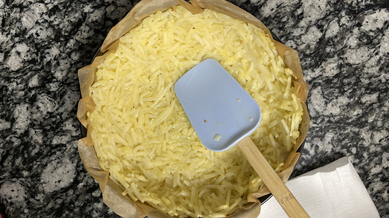 pressing hash browns in parchment paper-lined pan