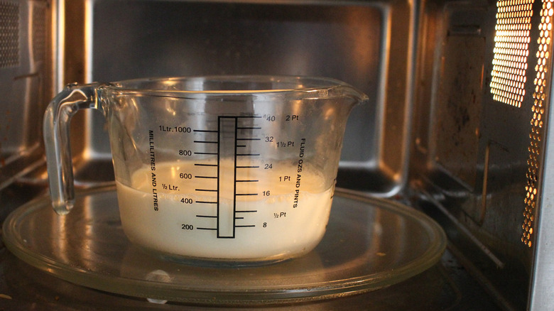 Measuring cup of milk in microwave