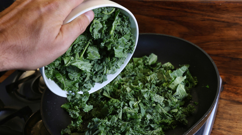 adding chopped kale to skillet