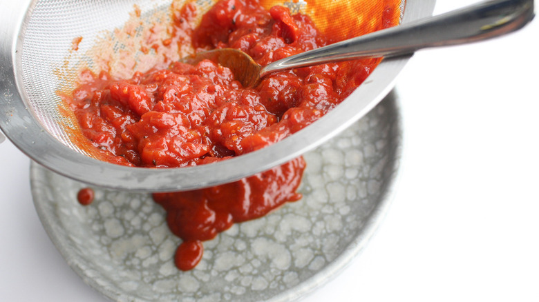 straining ketchup through sieve