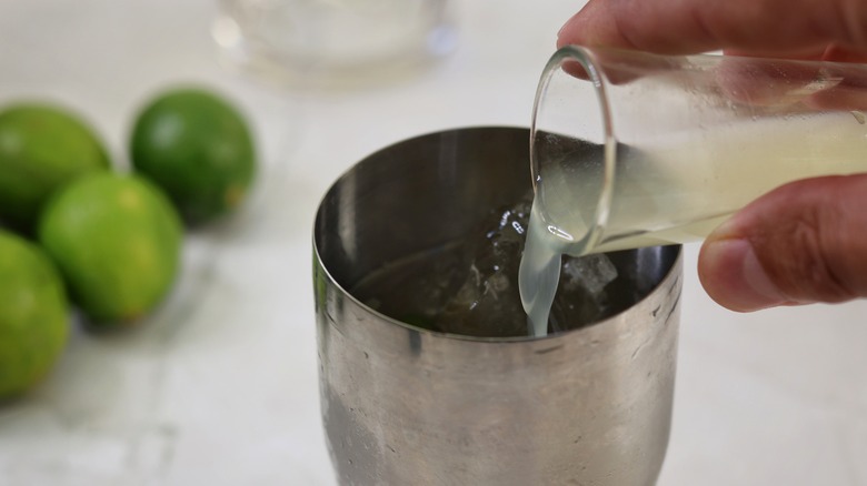 pouring lime juice into cocktail shaker