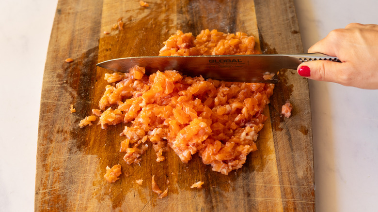 chopped raw salmon on cutting board with knife