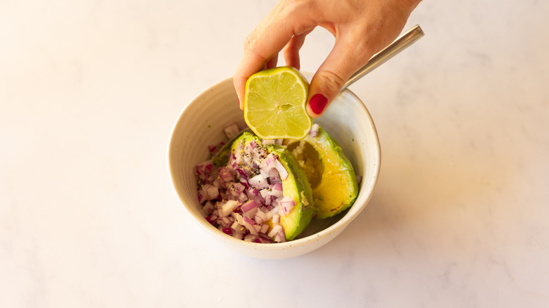 hand squeezing lime juice into guacamole