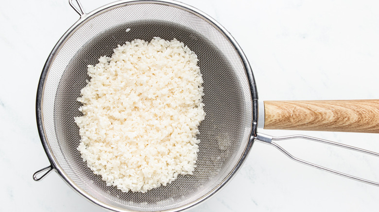 Sushi rice rinsed in sieve