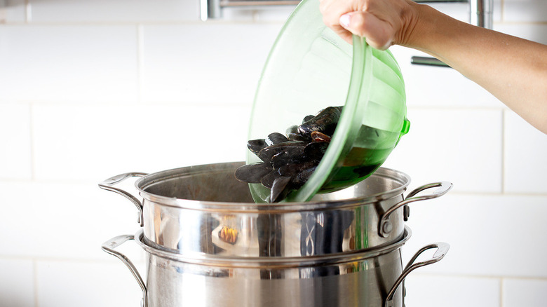 adding a bowl of mussels to spicy seafood boil pot