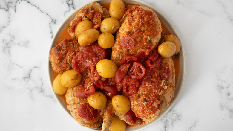 piri piri chicken with tomatoes and potatoes on plate