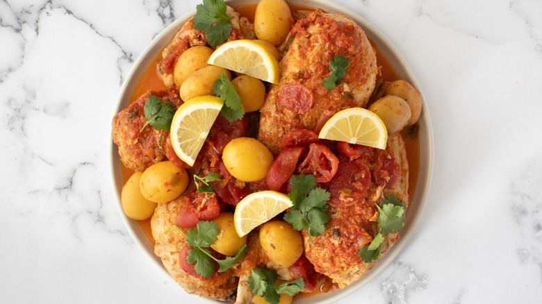 piri piri chicken with tomatoes and potatoes on serving platter